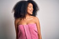 Young african american woman with afro hair wearing a body towel after beauty care shower looking away to side with smile on face, Royalty Free Stock Photo