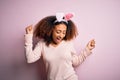 Young african american woman with afro hair wearing bunny ears over pink background Dancing happy and cheerful, smiling moving Royalty Free Stock Photo