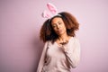 Young african american woman with afro hair wearing bunny ears over pink background looking at the camera blowing a kiss with hand Royalty Free Stock Photo