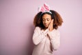 Young african american woman with afro hair wearing bunny ears over pink background sleeping tired dreaming and posing with hands Royalty Free Stock Photo