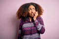 Young african american woman with afro hair wearing colorful shirt over pink background looking stressed and nervous with hands on