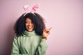 Young african american woman with afro hair wearing easter rabbit ears costume over pink background with a big smile on face, Royalty Free Stock Photo