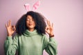 Young african american woman with afro hair wearing easter rabbit ears costume over pink background relax and smiling with eyes Royalty Free Stock Photo