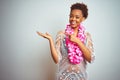 Young african american woman with afro hair wearing flower hawaiian lei over isolated background amazed and smiling to the camera Royalty Free Stock Photo
