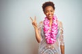 Young african american woman with afro hair wearing flower hawaiian lei over isolated background smiling with happy face winking Royalty Free Stock Photo