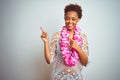 Young african american woman with afro hair wearing flower hawaiian lei over isolated background smiling and looking at the camera Royalty Free Stock Photo