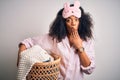 Young african american woman with afro hair wearing pajama doing laundry domestic chores cover mouth with hand shocked with shame