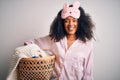 Young african american woman with afro hair wearing pajama doing laundry domestic chores with a happy face standing and smiling