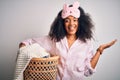 Young african american woman with afro hair wearing pajama doing laundry domestic chores very happy and excited, winner expression