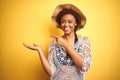 Young african american woman with afro hair wearing summer hat over white isolated background amazed and smiling to the camera Royalty Free Stock Photo