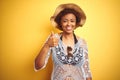 Young african american woman with afro hair wearing summer hat over white isolated background doing happy thumbs up gesture with Royalty Free Stock Photo