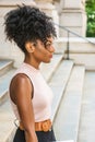 Young African American woman with afro hairstyle, white ear bead pin, wearing sleeveless light color top, dark orange belt, black Royalty Free Stock Photo