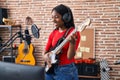 Young african american woman artist singing song playing electrical guitar at music studio Royalty Free Stock Photo