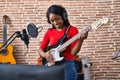 Young african american woman artist singing song playing electrical guitar at music studio Royalty Free Stock Photo