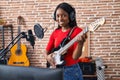 Young african american woman artist singing song playing electrical guitar at music studio Royalty Free Stock Photo