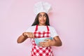 Young african american woman with braids cooking using baker whisk smiling looking to the side and staring away thinking Royalty Free Stock Photo