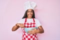 Young african american woman with braids cooking using baker whisk winking looking at the camera with sexy expression, cheerful Royalty Free Stock Photo