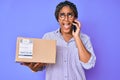 Young african american woman with braids holding delivery box calling assistance angry and mad screaming frustrated and furious, Royalty Free Stock Photo