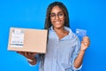 Young african american woman with braids holding delivery box and credit card smiling with a happy and cool smile on face Royalty Free Stock Photo