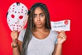 Young african american woman with braids holding halloween banner and scary mask depressed and worry for distress, crying angry