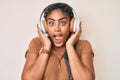 Young african american woman with braids listening to music using headphones celebrating crazy and amazed for success with open Royalty Free Stock Photo