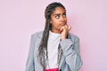 Young african american woman with braids wearing business jacket serious face thinking about question with hand on chin, Royalty Free Stock Photo