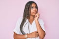 Young african american woman with braids wearing casual summer shirt serious face thinking about question with hand on chin, Royalty Free Stock Photo