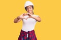 Young african american woman with braids wearing hardhat and builder clothes smiling in love showing heart symbol and shape with