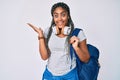 Young african american woman with braids wearing student backpack and headphones celebrating victory with happy smile and winner Royalty Free Stock Photo