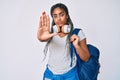 Young african american woman with braids wearing student backpack and headphones with open hand doing stop sign with serious and Royalty Free Stock Photo