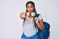 Young african american woman with braids wearing student backpack and headphones pointing with finger to the camera and to you, Royalty Free Stock Photo