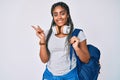 Young african american woman with braids wearing student backpack and headphones smiling happy pointing with hand and finger to Royalty Free Stock Photo