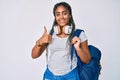 Young african american woman with braids wearing student backpack and headphones smiling happy and positive, thumb up doing Royalty Free Stock Photo