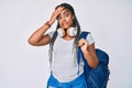 Young african american woman with braids wearing student backpack and headphones stressed and frustrated with hand on head, Royalty Free Stock Photo