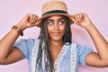 Young african american woman with braids wearing summer hat smiling looking to the side and staring away thinking Royalty Free Stock Photo