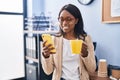 Young african american woman business worker using smartphone drinking coffee at office Royalty Free Stock Photo