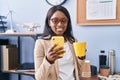 Young african american woman business worker using smartphone drinking coffee at office Royalty Free Stock Photo