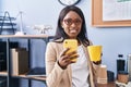 Young african american woman business worker using smartphone drinking coffee at office Royalty Free Stock Photo