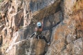 Young african american woman climbs along granite cliff. girl holds on to the safety rope for the descent from the cliff