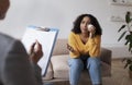 Young African American woman crying on session with psychologist, speaking to mental health professional at office Royalty Free Stock Photo