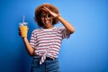 Young African American woman with curly hair on vacation wearing hat drinking orange juice with happy face smiling doing ok sign Royalty Free Stock Photo