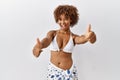 Young african american woman with curly hair wearing bikini approving doing positive gesture with hand, thumbs up smiling and Royalty Free Stock Photo