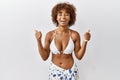 Young african american woman with curly hair wearing bikini success sign doing positive gesture with hand, thumbs up smiling and Royalty Free Stock Photo