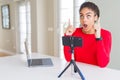 Young african american woman doing video call using smartphone camera amazed and surprised looking up and pointing with fingers Royalty Free Stock Photo