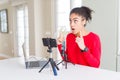 Young african american woman doing video call using smartphone camera and microphone amazed and surprised looking up and pointing Royalty Free Stock Photo