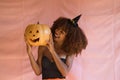 Young african american woman dressed as a witch for halloween party and holding a pumpkin in her hands. She wears a witch`s hat Royalty Free Stock Photo