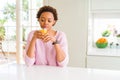 Young african american woman driking orange juice at home with a confident expression on smart face thinking serious Royalty Free Stock Photo