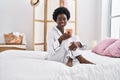 Young african american woman drinking cup of coffee sitting on bed at bedroom Royalty Free Stock Photo
