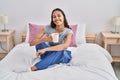 Young african american woman drinking cup of coffee sitting on bed at bedroom Royalty Free Stock Photo