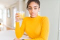 Young african american woman drinking a glass of fresh orange juice with a confident expression on smart face thinking serious Royalty Free Stock Photo